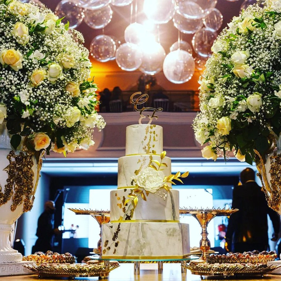 Bolo de casamento e mesa de doces sob luzes